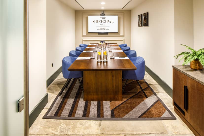 Cavern meeting room at Municipal Hotel Liverpool with wooden table and blue chairs.