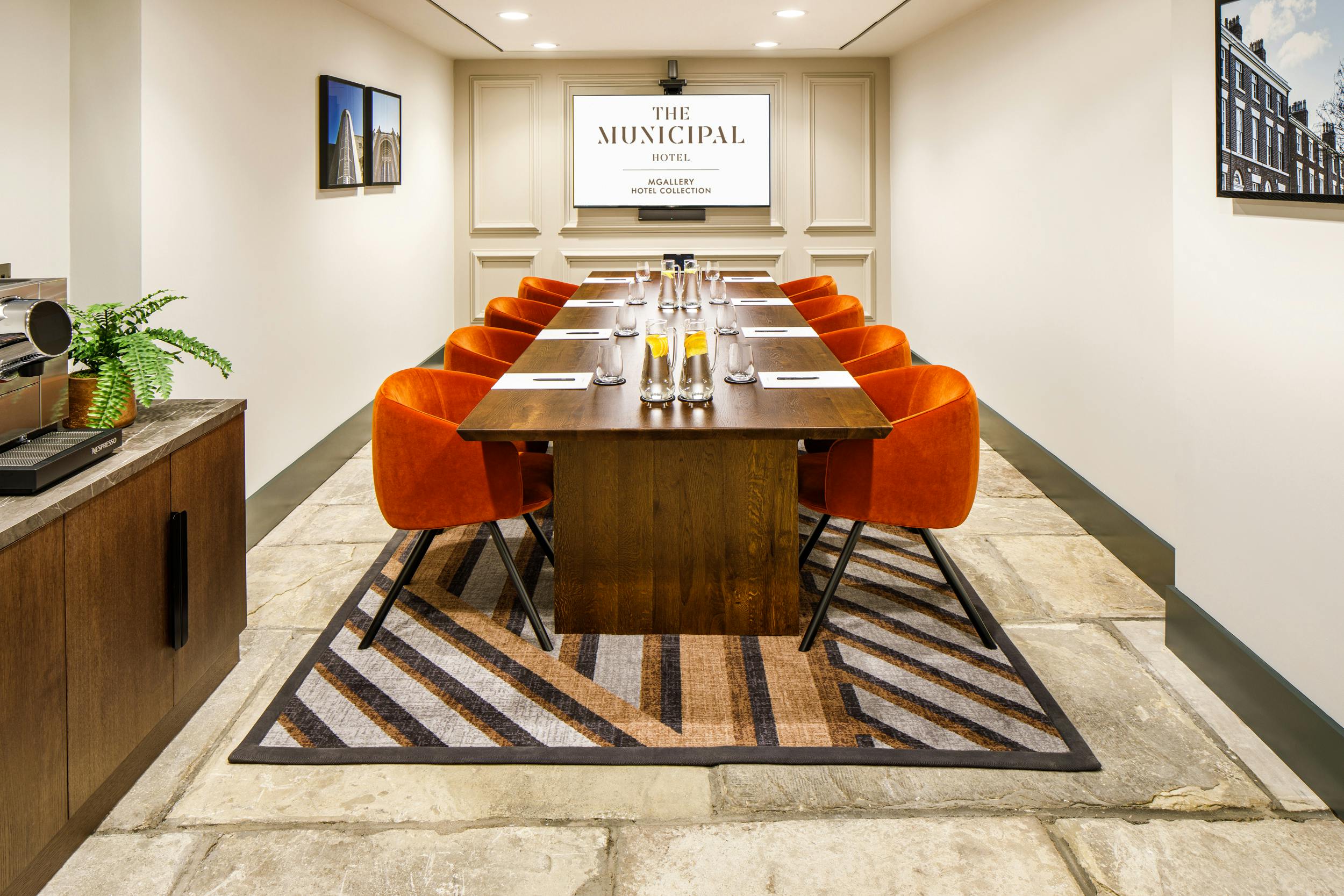 Meeting room with wooden table and orange chairs at Municipal Hotel Liverpool.