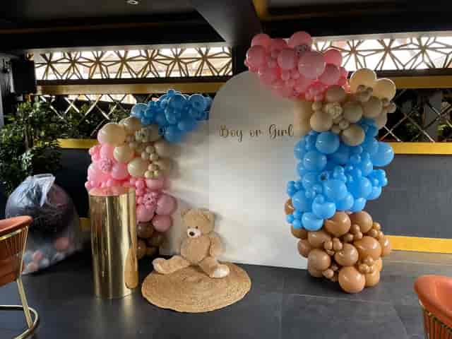 Gender reveal event backdrop with pastel balloon arch and teddy bear decor.