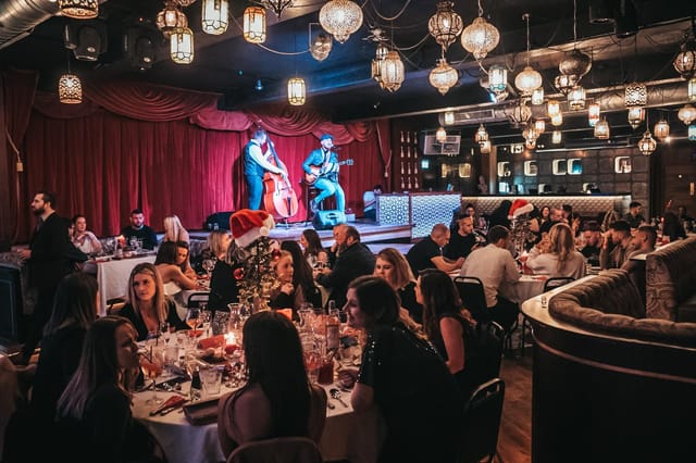 Vibrant Impossible Theatre event space with live performers and elegant dining setup.