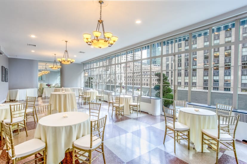 Elegant Solarium at 3 West Club, featuring round tables and city views for events.
