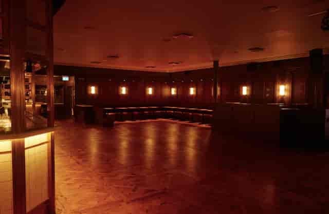 Alt text: "The Ballroom in NEON194, a warm-lit event space with polished wooden floor for gatherings."