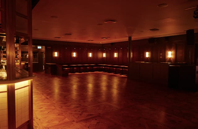 Alt text: "The Ballroom in NEON194, a warm-lit event space with polished wooden floor for gatherings."