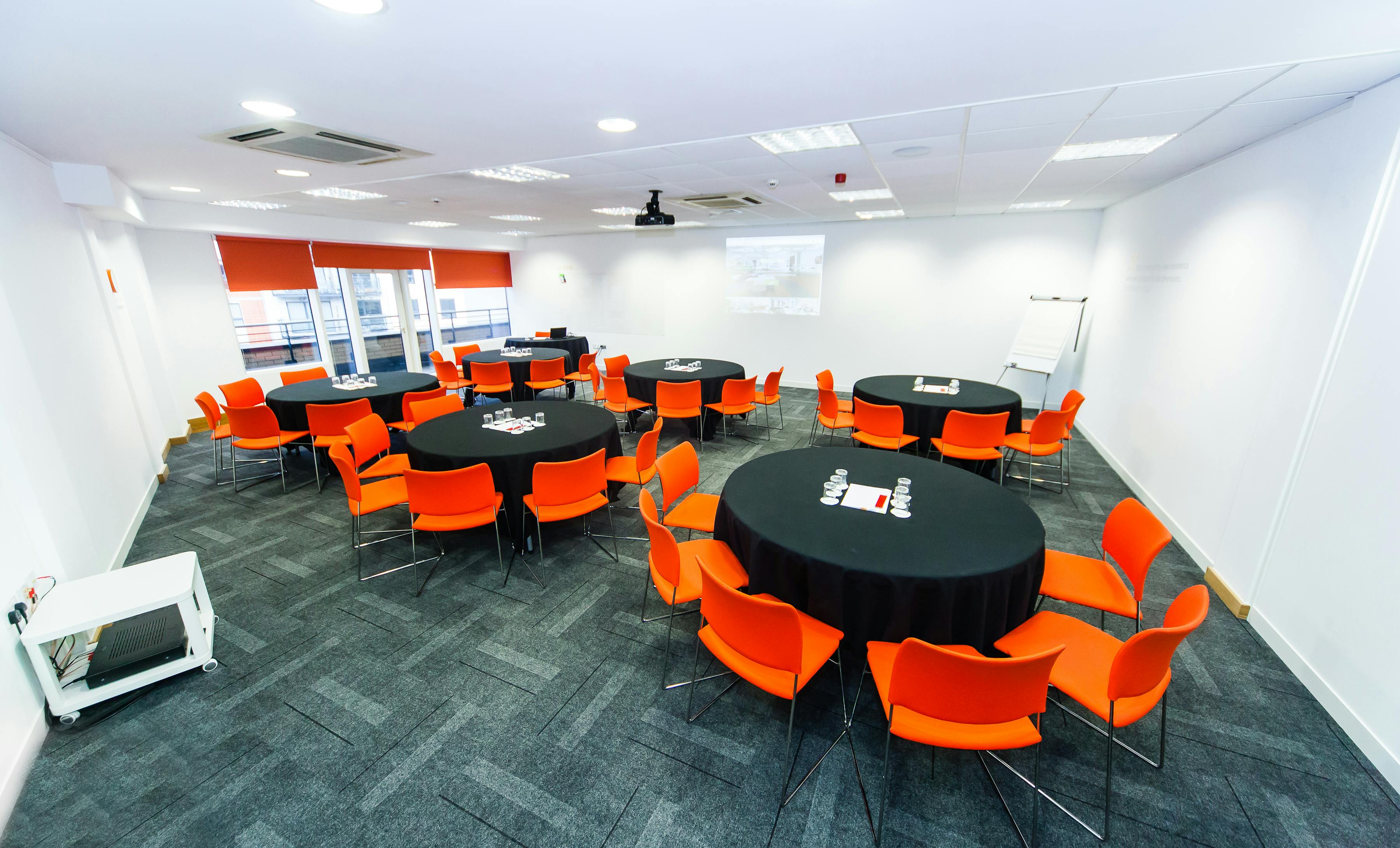 Collaborative meeting space in Leeds with vibrant orange chairs for engaging events.