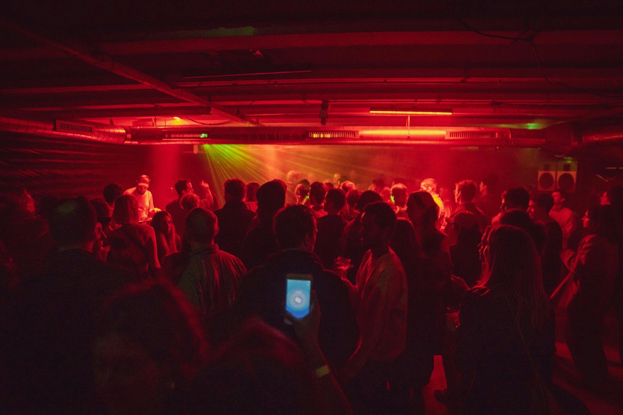 Vibrant event atmosphere in Strange Brew's back room with dynamic red lighting.