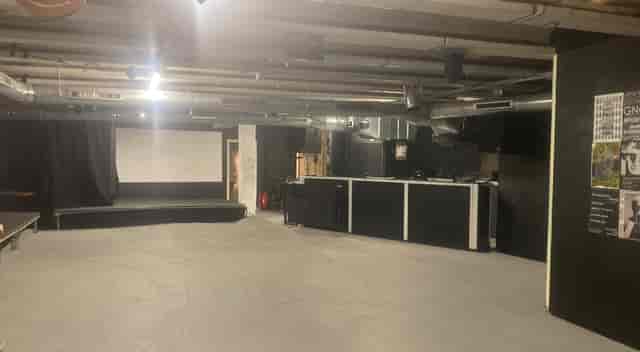 Versatile minimalist event space with stage and bar at Strange Brew for gatherings.