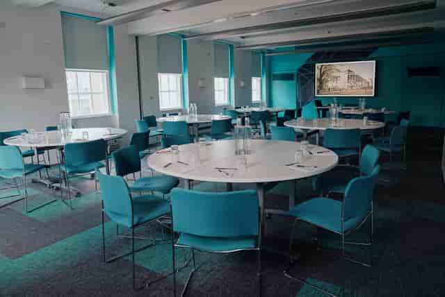 Modern meeting space with circular tables and turquoise accents for workshops and corporate events.