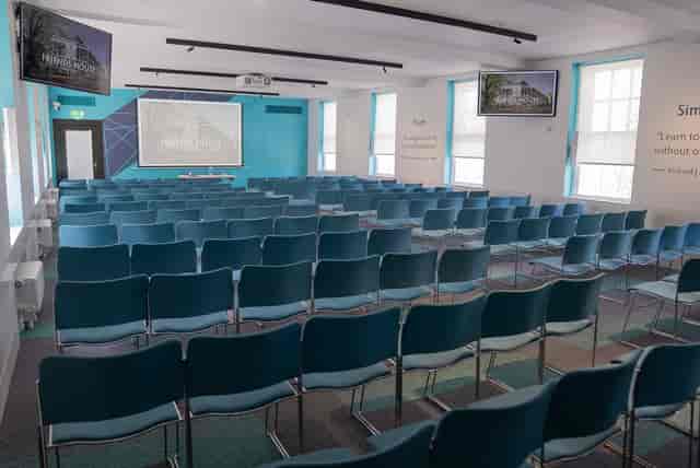 Event space with teal chairs and large screen for presentations and conferences.