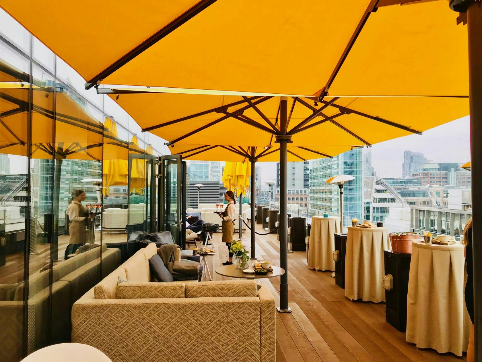 Stylish rooftop event space with yellow umbrellas, ideal for networking and social gatherings.