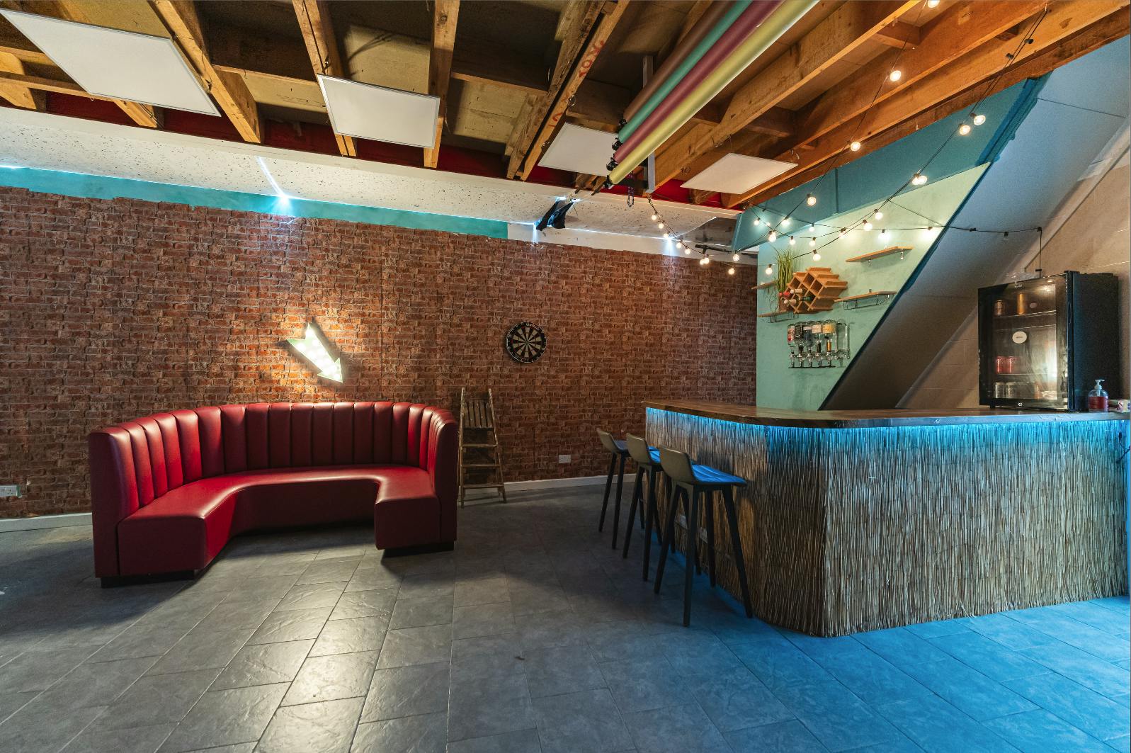 Modern event space with cozy red sofa and bar, ideal for networking and gatherings.