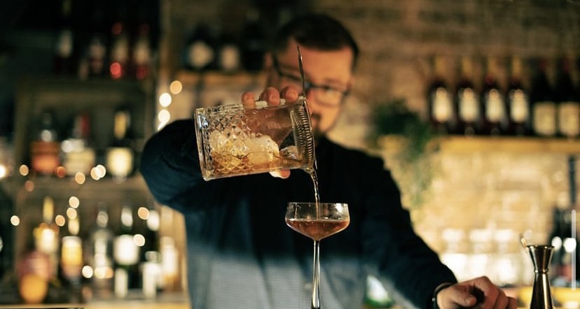 Bartender pouring cocktail at Berlin Lounge, perfect for networking events and social gatherings. - Banner