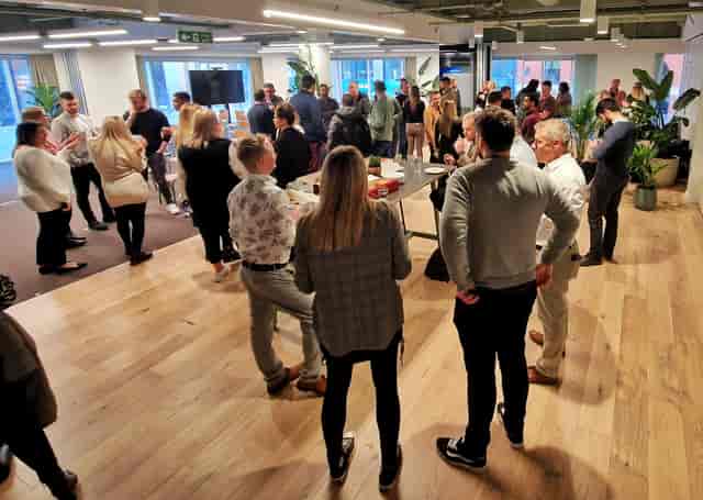 Vibrant networking event in modern Foundry office space with greenery and engaged attendees.