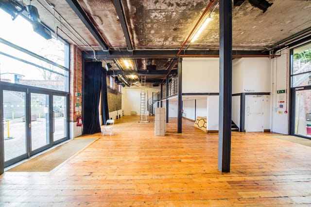 Versatile industrial event space with large windows for meetings and workshops.