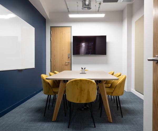 Modern meeting room in Runway East Shoreditch with sleek table and yellow chairs.