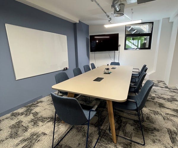 Modern conference room with spacious table and large screen for collaborative meetings.