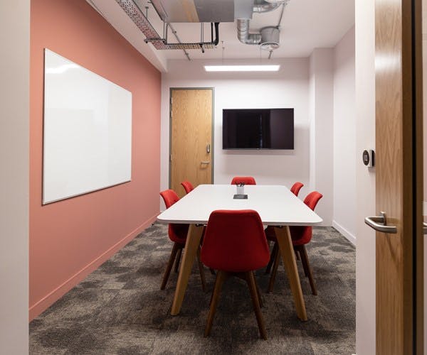 Modern meeting room with white table and red chairs, perfect for team brainstorming sessions.