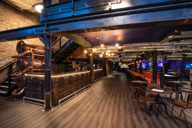 Industrial-chic event space at Strike Bowling with cozy bar for gatherings and meetings.