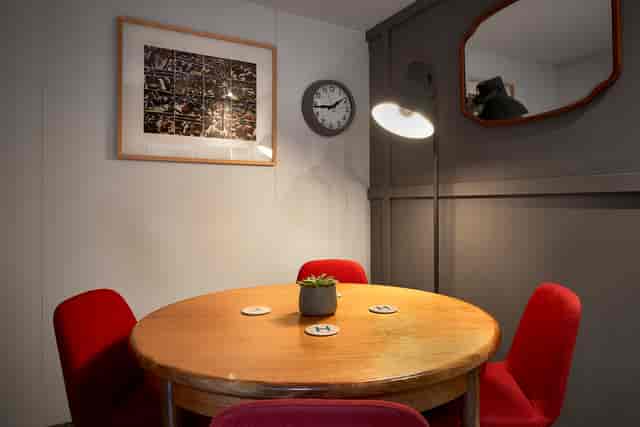 Cozy meeting room with round table and red chairs, perfect for brainstorming sessions.