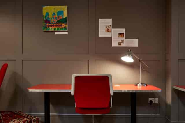 Minimalist meeting space with red desk, ideal for workshops and group sessions.