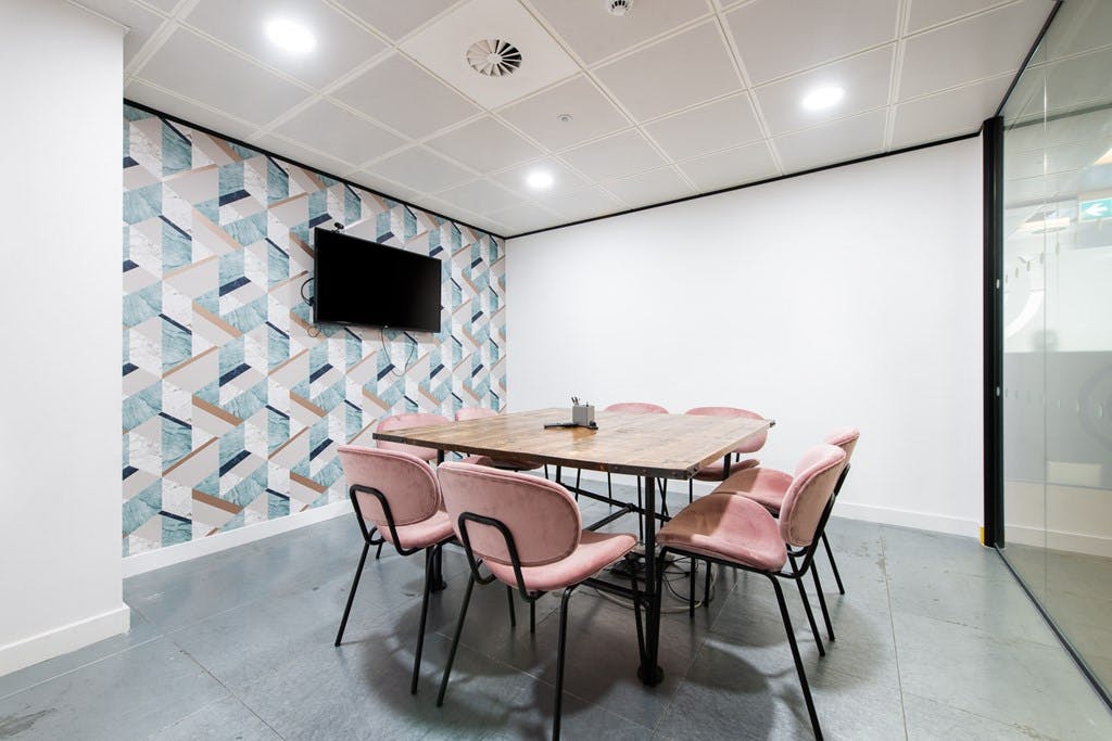 Modern meeting room with stylish table, pink chairs, ideal for events and presentations.