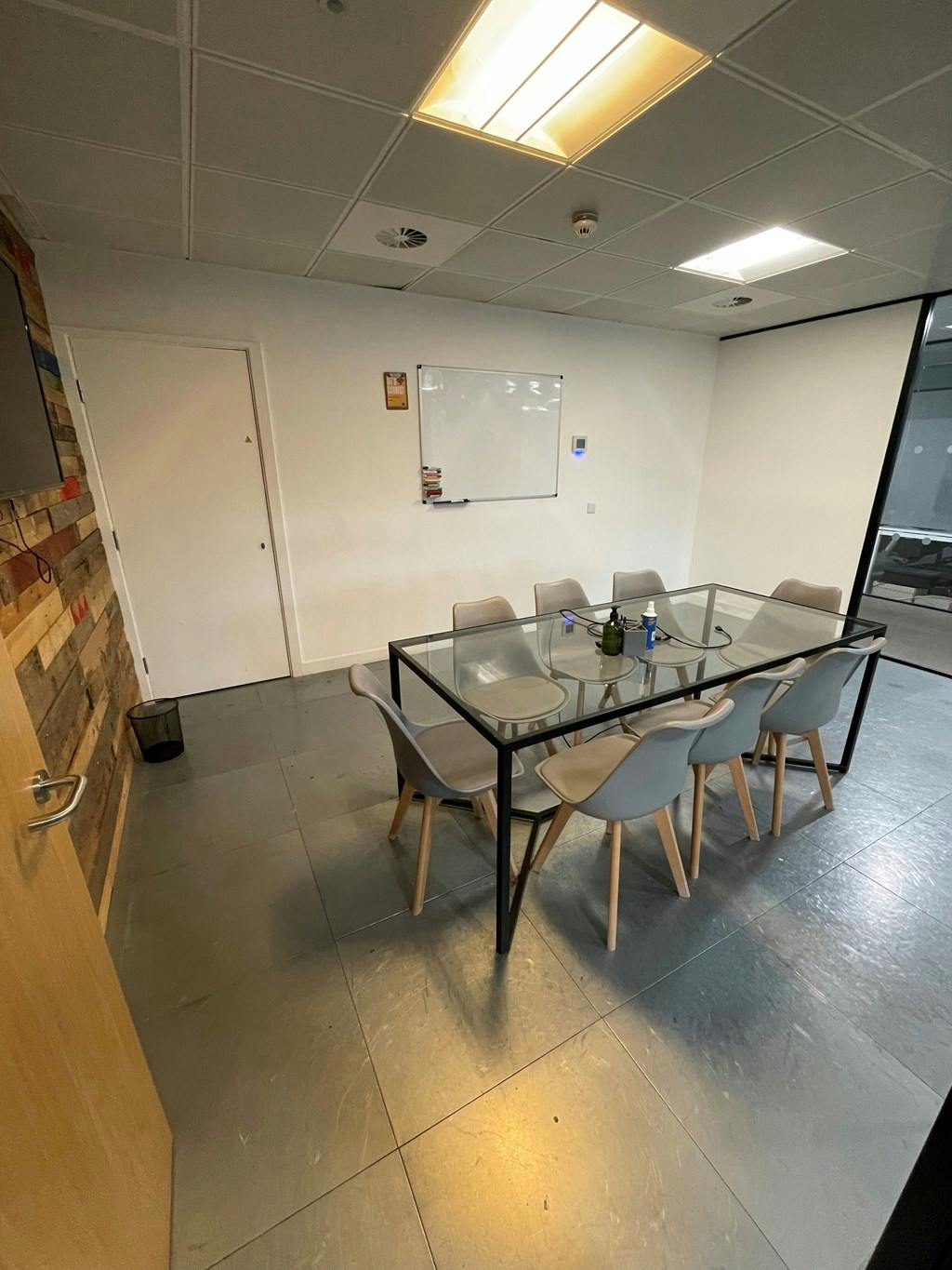 John in modern meeting room with glass table, ideal for workshops and discussions.