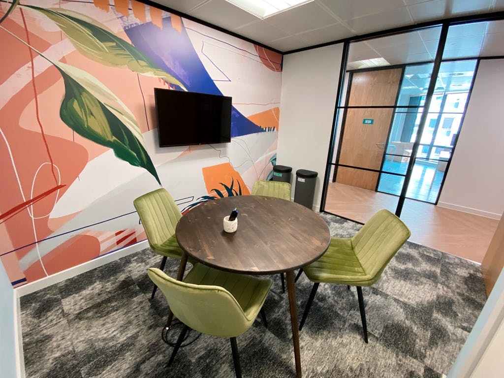 Harriet in modern meeting space with round table and green chairs for creative workshops.