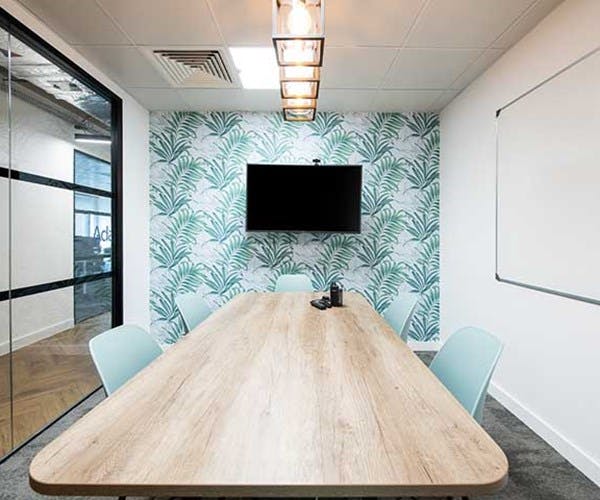 Modern meeting room with wooden table and tropical wallpaper for collaborative events.