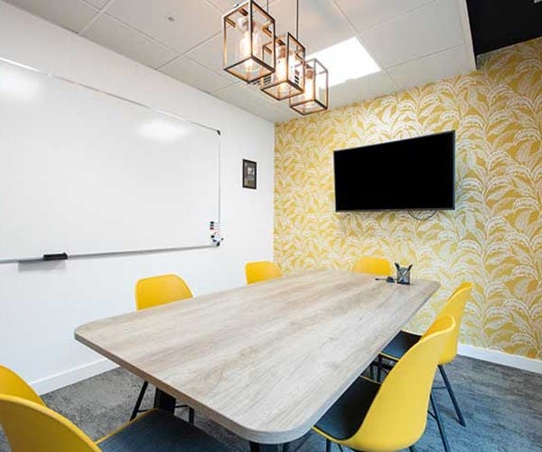 Modern meeting room at Runway East Temple Meads with wooden table and yellow chairs.