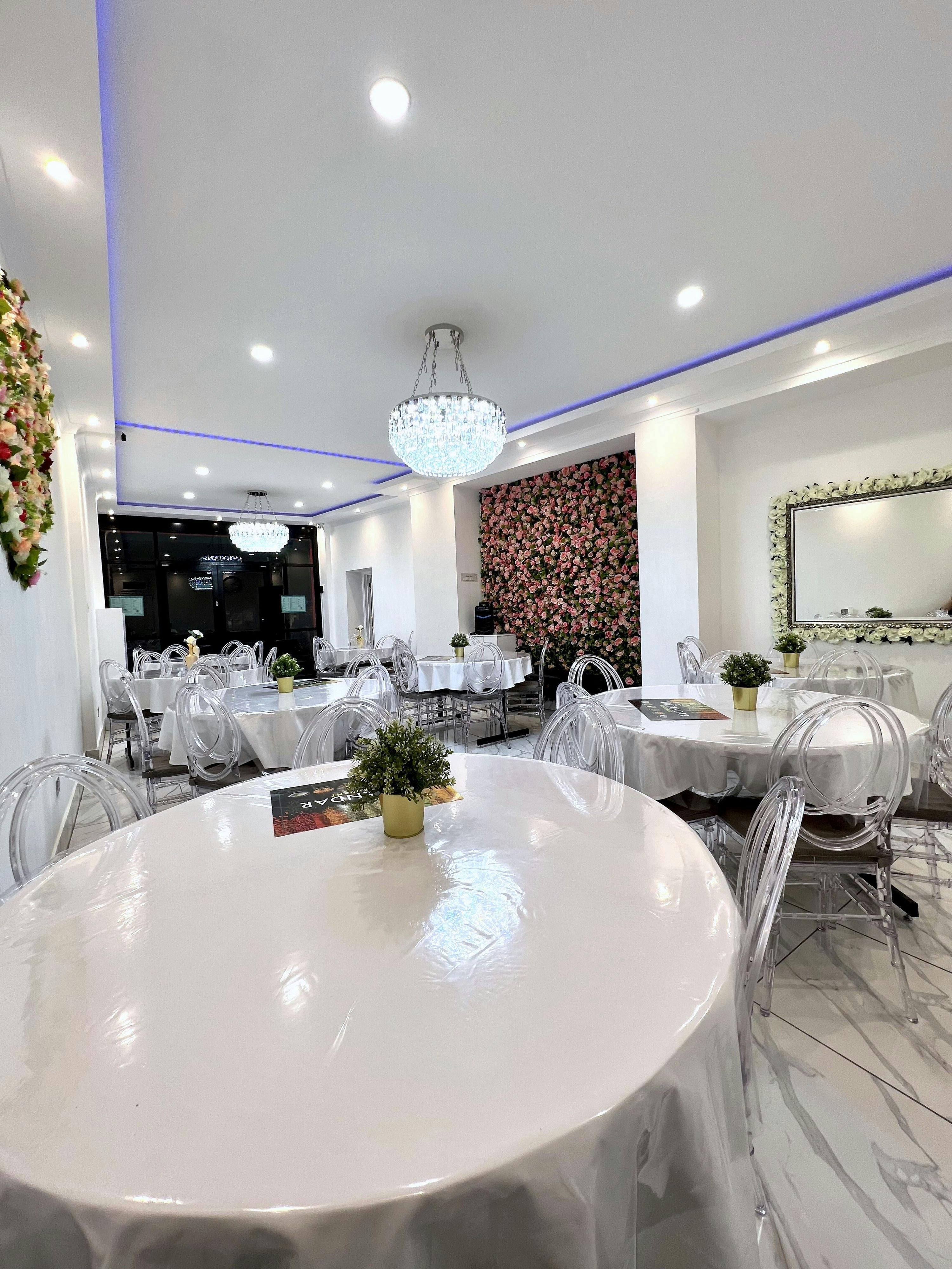 Modern Watandar Hall with elegant round tables and floral accent wall for upscale events.