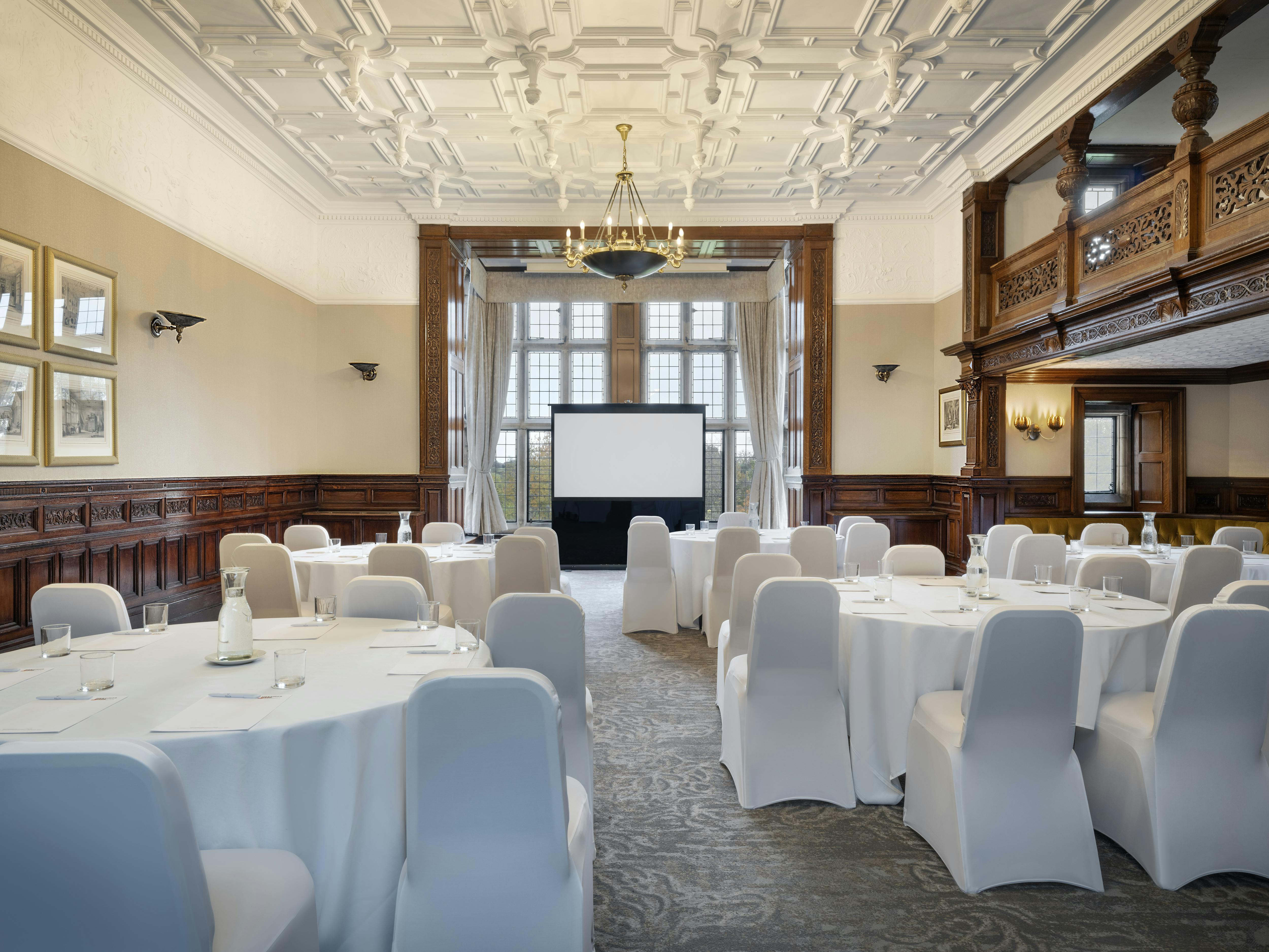 Haslam Room at Delta Hotels: elegant corporate meeting space with round tables and large windows.