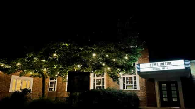 Esher Theatre at night, illuminated facade and marquee for events in a charming setting.
