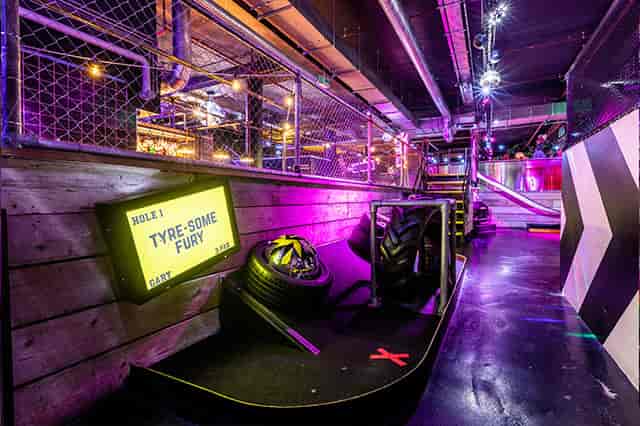 Vibrant Junkyard Golf Club event space with neon lights for team-building activities.