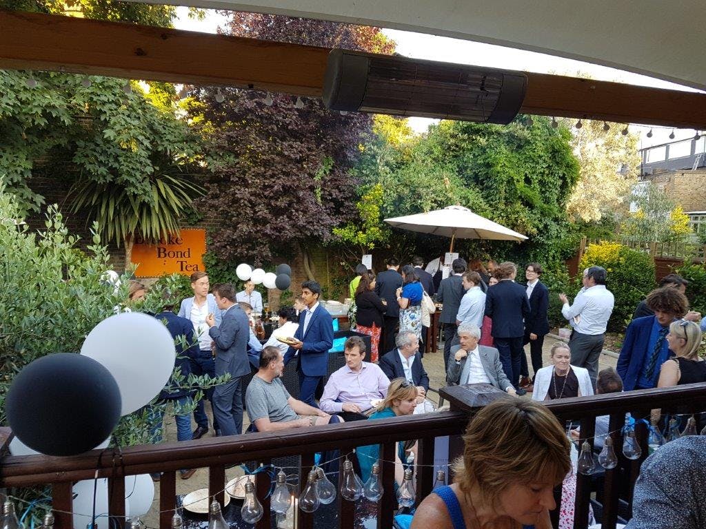 Outdoor networking event at The Boathouse, featuring elegant decor and greenery.