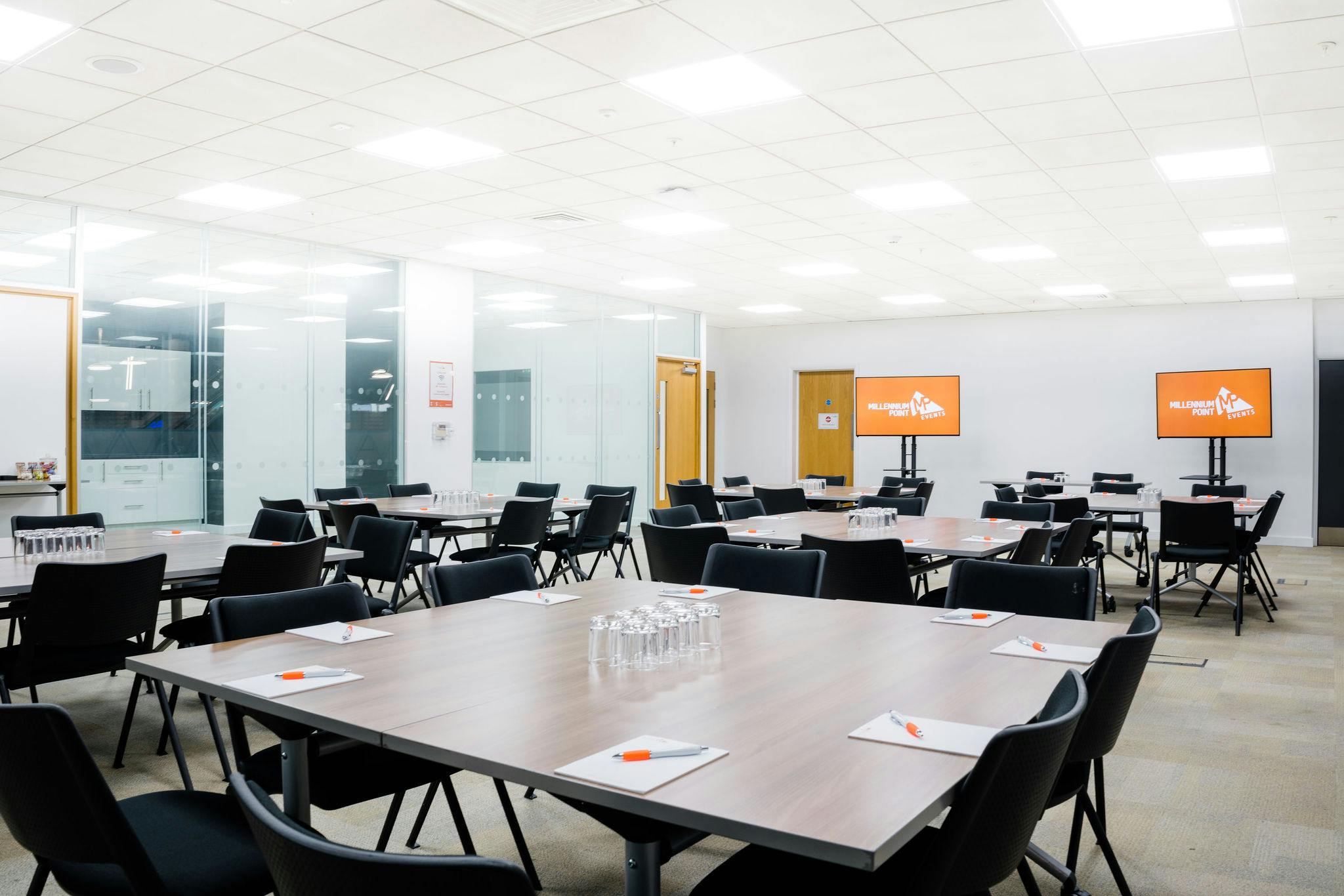 Meeting room at Millennium Point, featuring tables for collaboration and presentation screens.