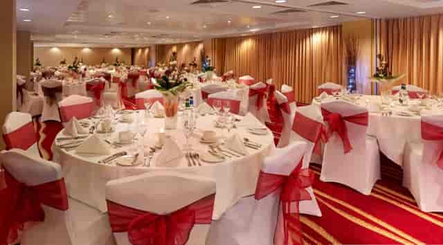 Elegant banquet hall with white linens and red accents for weddings and corporate events.
