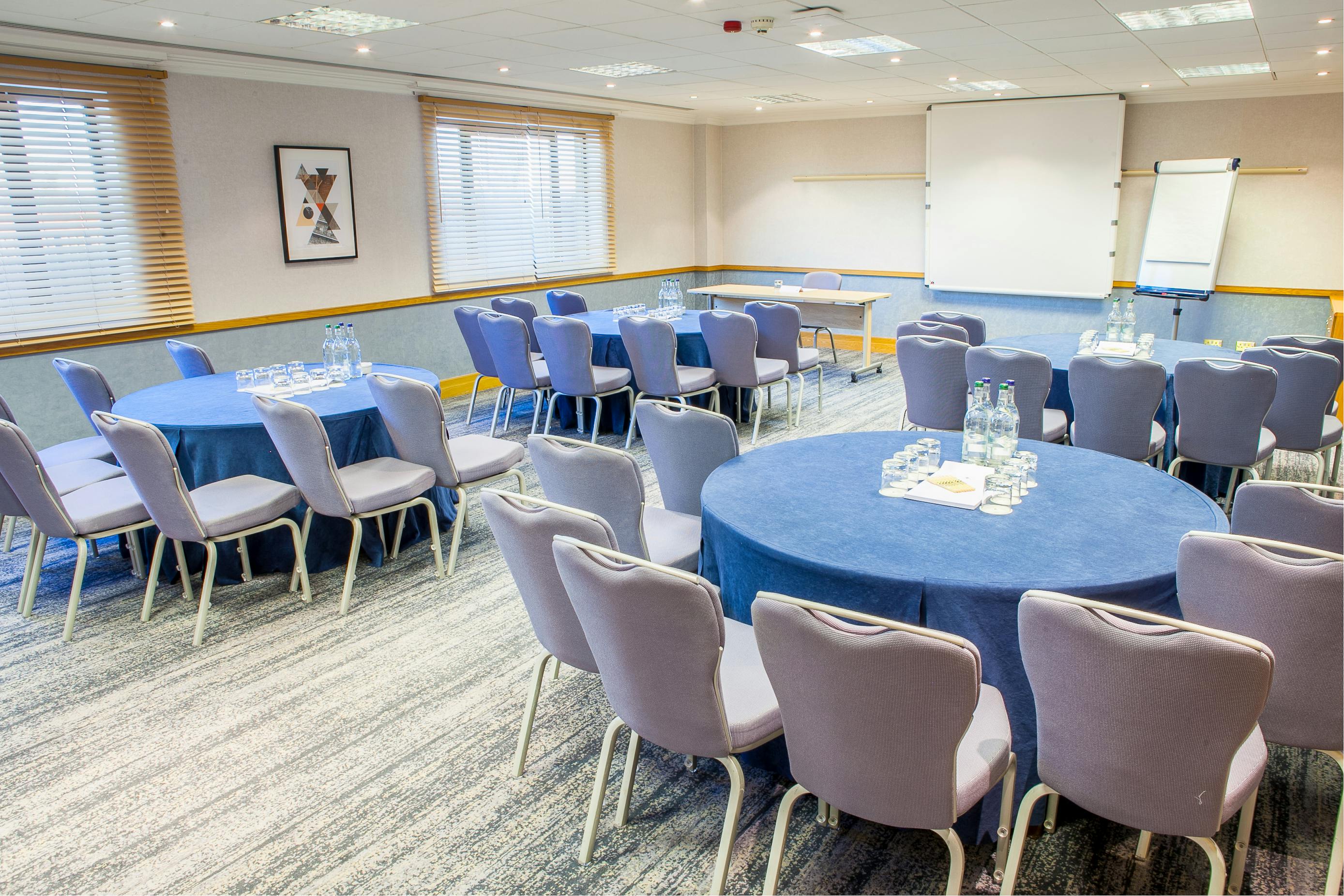 Hawksworth Suite meeting room with circular tables, ideal for professional events and networking.