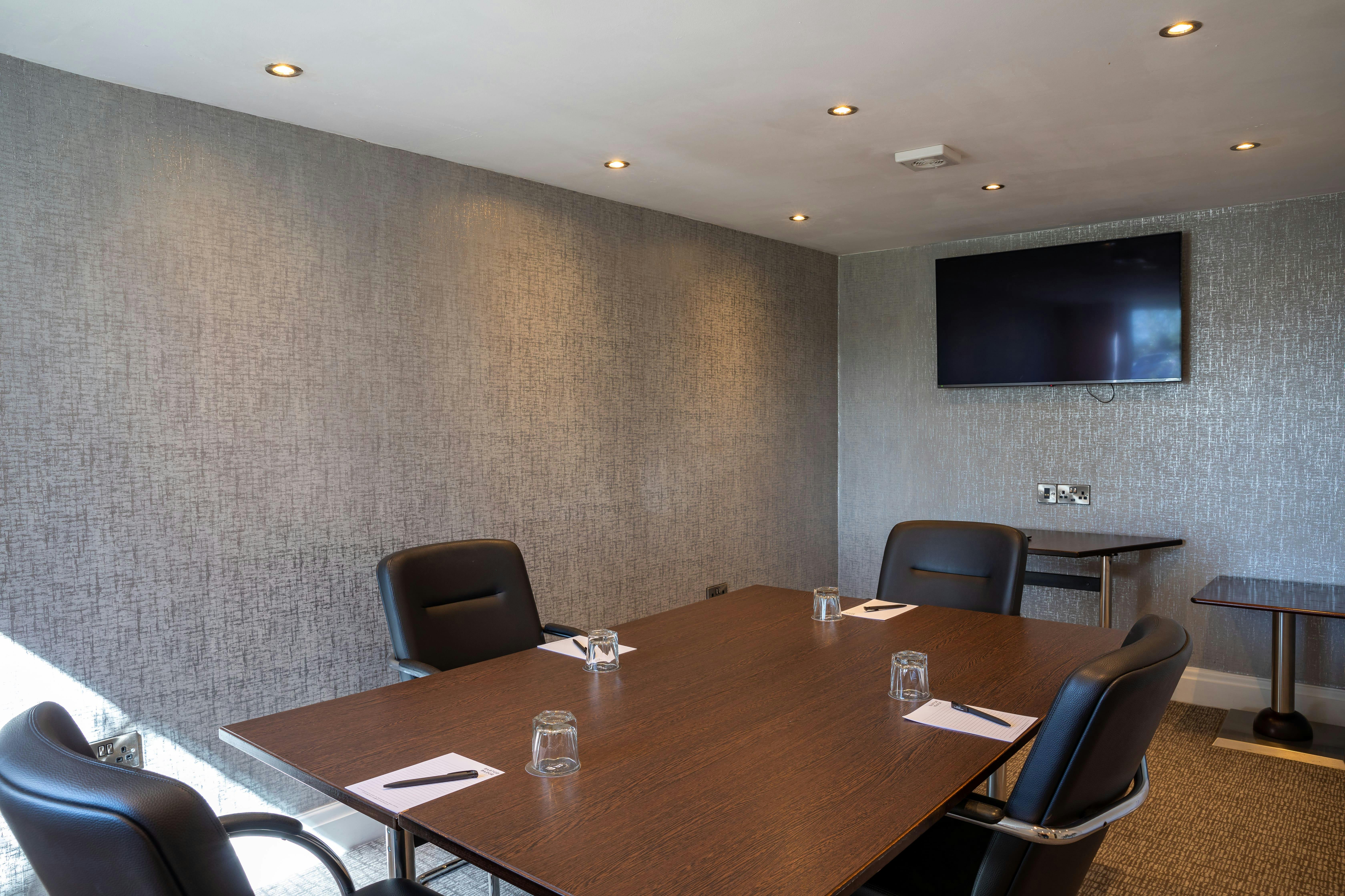 Modern meeting room at Barton Manor Hotel with dark wood table, ideal for conferences.