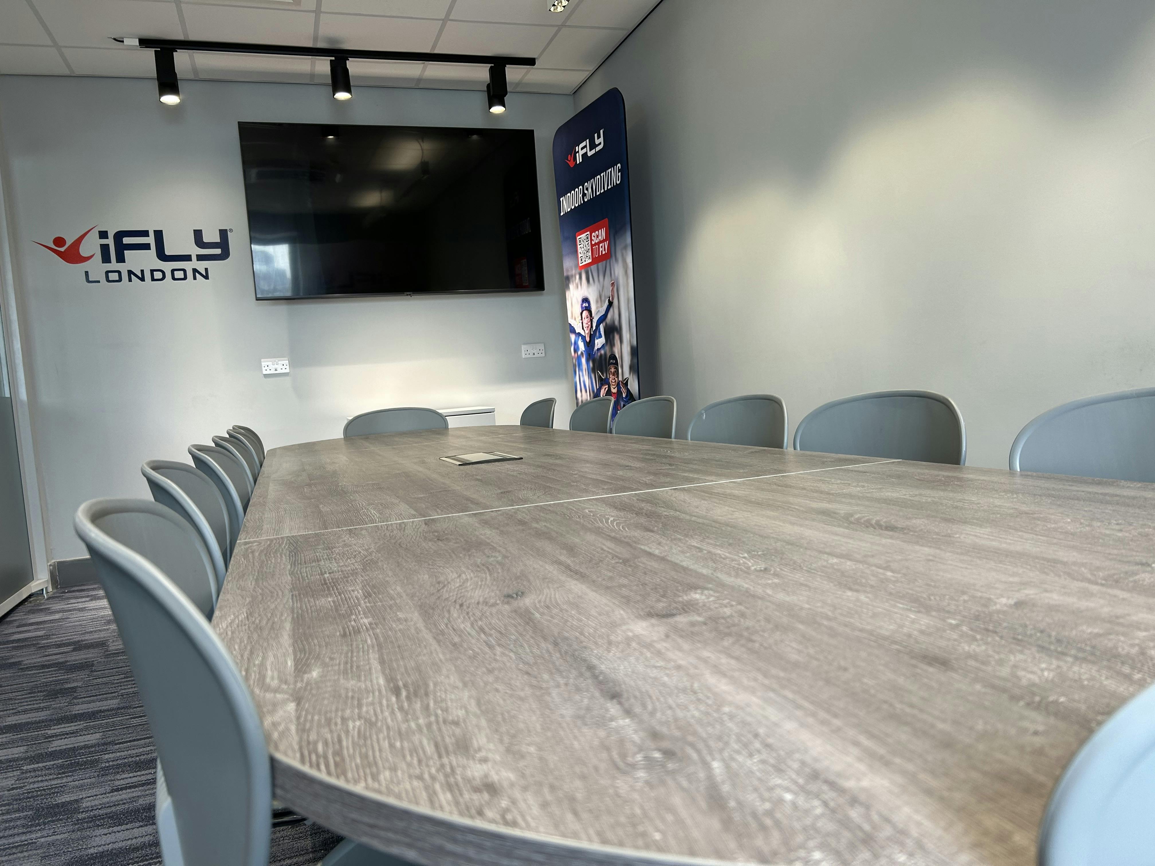 Modern conference room with wooden table at iFLY Indoor Skydiving, ideal for corporate events.