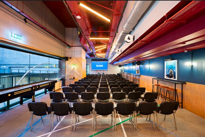 Modern conference space with black chairs and large screen at Bounce Battersea Power Station.