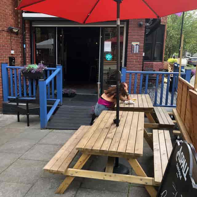 Outdoor seating at Neptune Bar with wooden tables and vibrant blue accents for casual events.