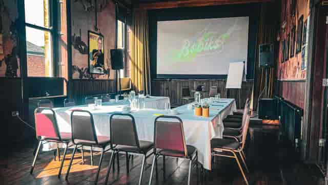 "Meeting space with large screen, seating for collaboration, ideal for workshops and events."