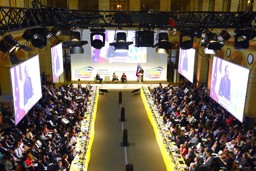 Conference setting in Palais Brongniart with central stage and engaged audience.