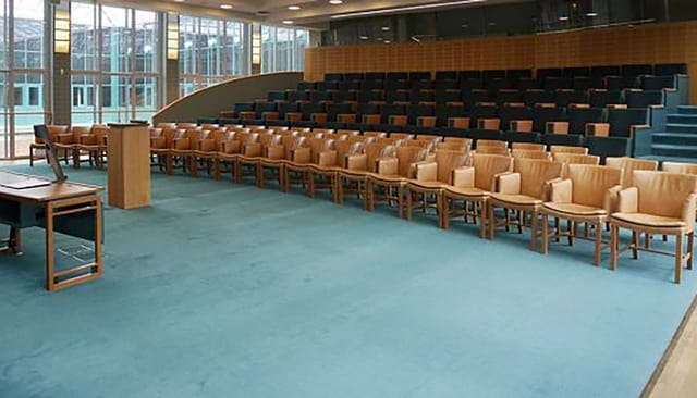 Spacious auditorium with wooden chairs, ideal for corporate meetings and lectures.