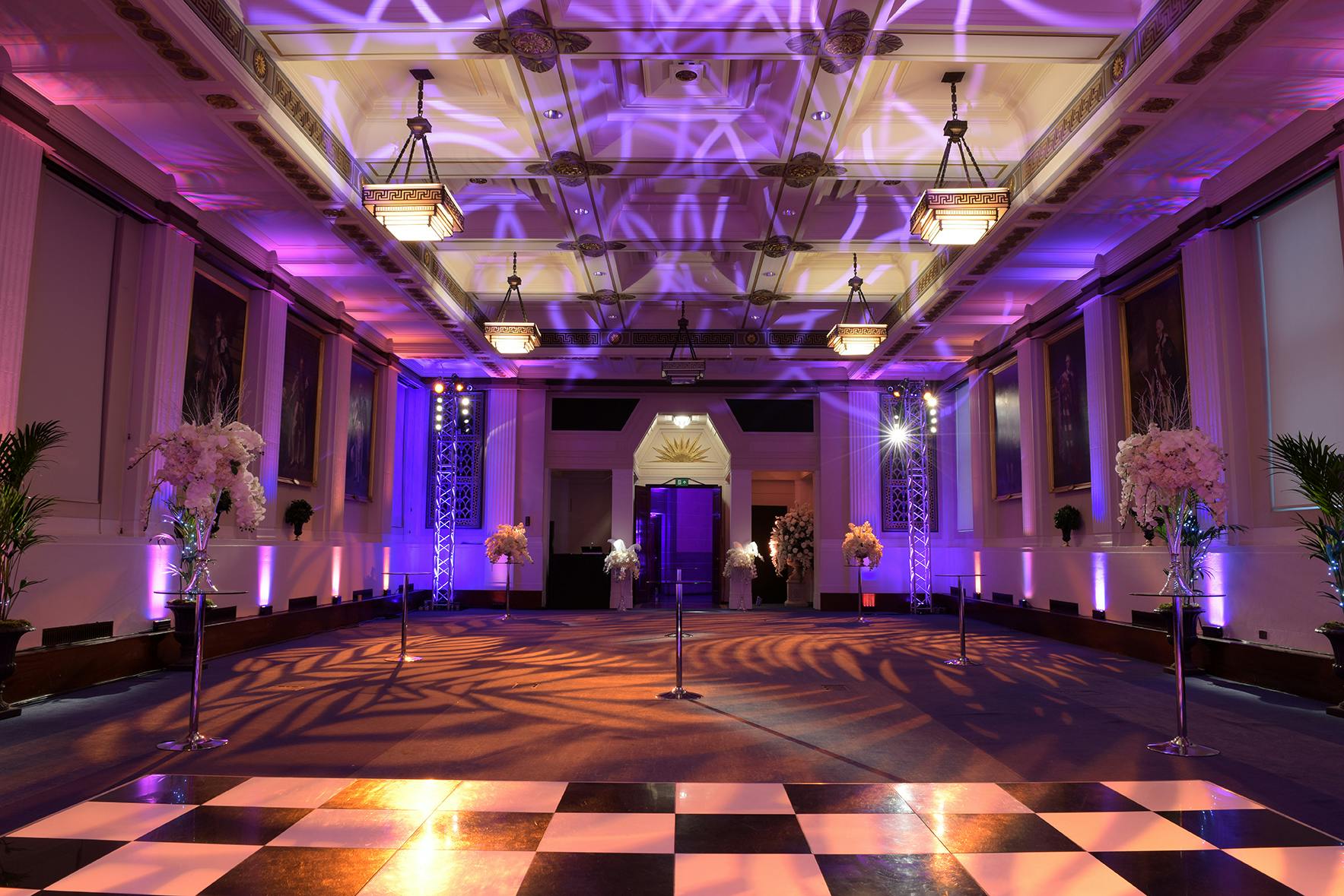 Elegant event space in The Gallery Suite with purple uplighting and checkered dance floor.