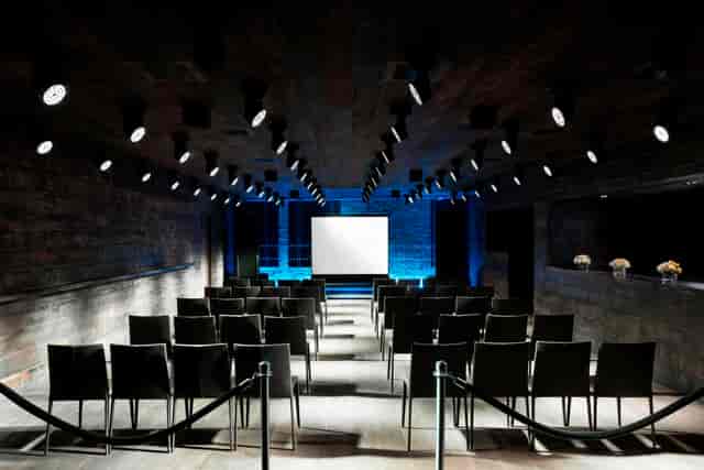 Modern event space with black chairs and projection screen for corporate meetings.