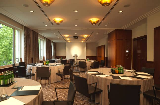 Meeting room at The Charles Hotel with round tables, ideal for workshops and conferences.