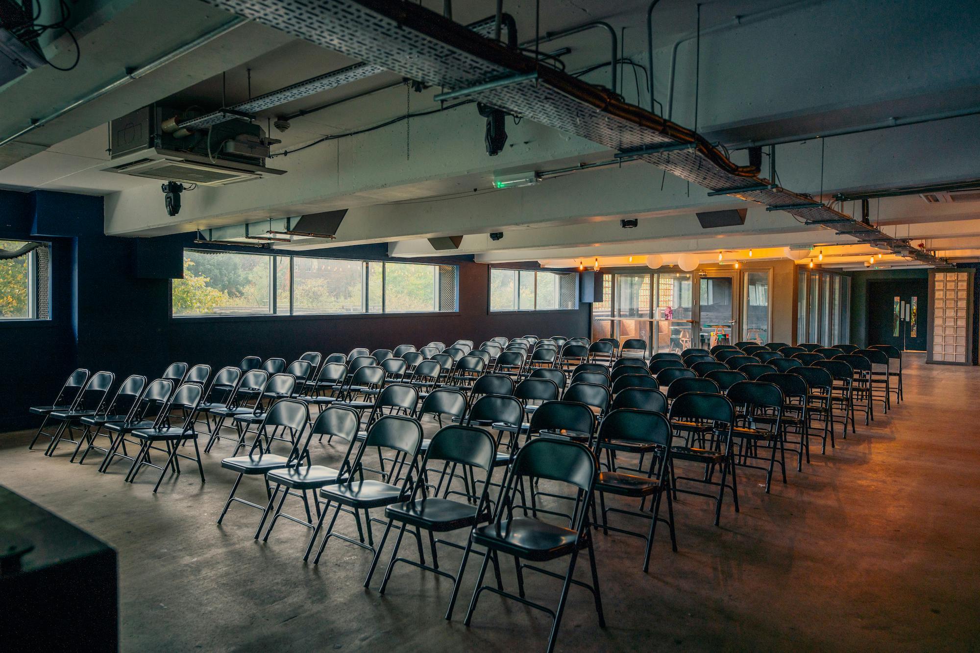 Versatile event space in Peckham Levels with black chairs for presentations and seminars.