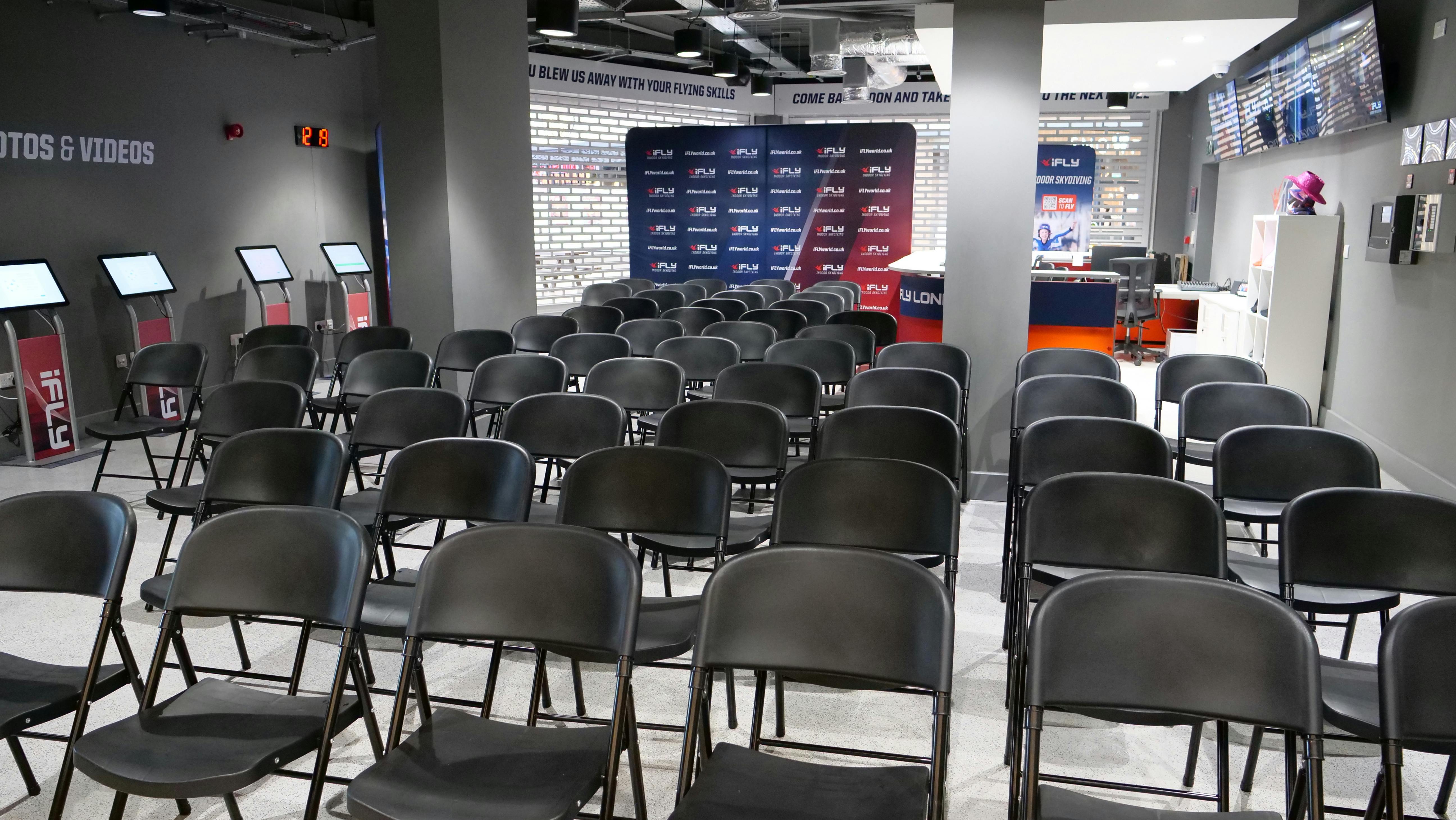 iFLY Indoor Skydiving event space with black chairs for presentations and panel discussions