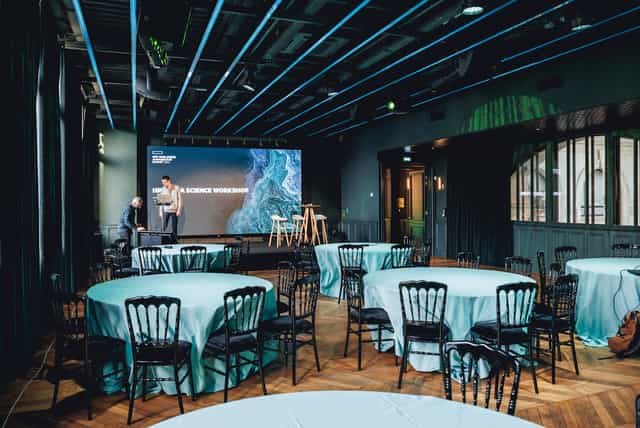 Event space with round tables and a speaker, ideal for conferences and workshops.