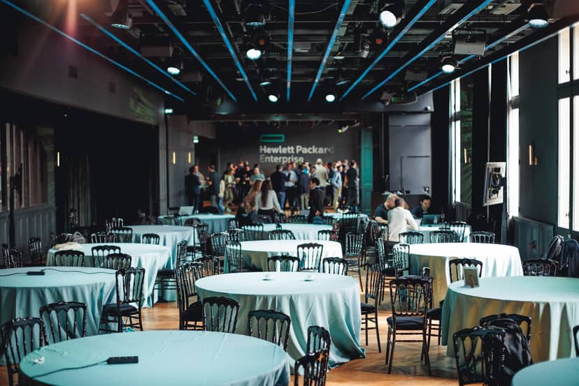 Event space with round tables and stage, perfect for corporate conferences or workshops.